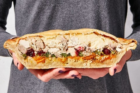 Holding a Turkey Dinner Pie, sliced in half to show a cross-section of filling