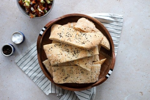 A bowl of Afghan naan topped with black and white sesame seeds
