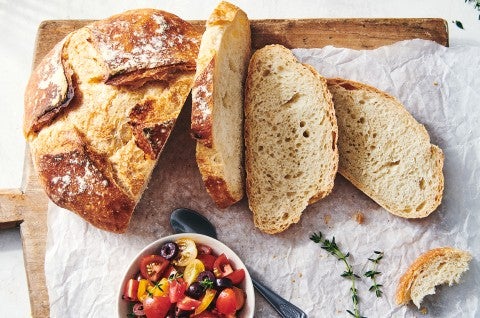 A loaf of crusty bread that has a few slices cut off, showing off the thin and crisp crust and even interior structure.