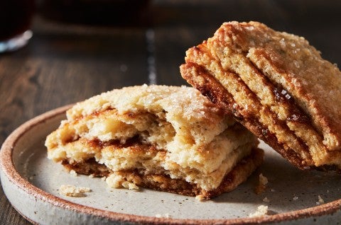 A Layered Fig Scone on a plate, broken in half, to reveal stripes of fig jam.