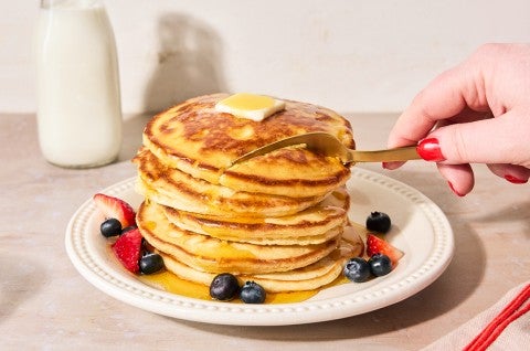 Easy Buttermilk Pancakes topped with maple syrup on a plate with fresh fruit