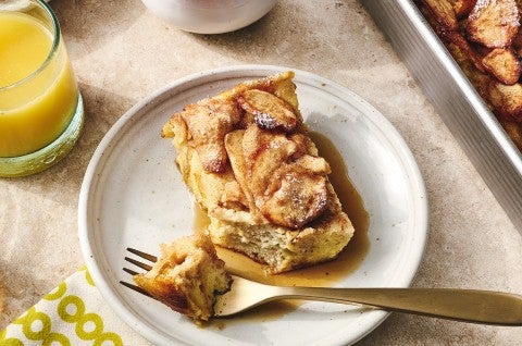 A slice of Apple French Toast Bake on a light colored plate with a bit atop a fork.