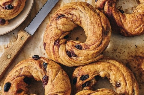 A handful of freshly baked Cinnamon Raisin Bagels on parchment paper seen from above.