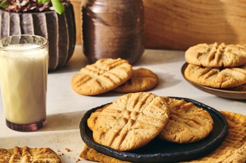 A photograph of Classic Peanut Butter Cookies on a plate with a glass of milk next to it.