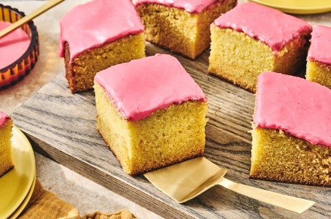 Cranberry-Orange Olive Oil Cake sliced up and arranged on a glass plate with a gold hued serving spatula under one of the golden slices.
