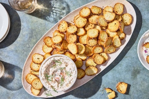 A platter of Everything Bagel Chips spread out around a small bowl of Smoked Salmon Cream Cheese dip.