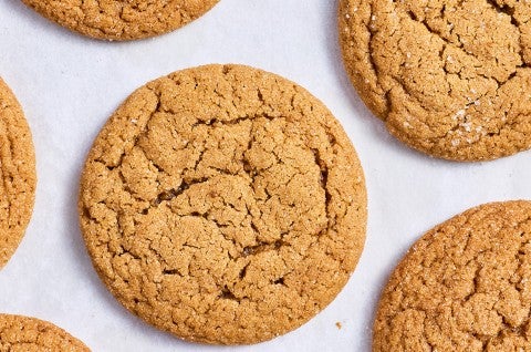 Soft Brown Sugar Cookies laid out on white parchment showing the top of the cookies with a soft cracked top and dark golden hues.