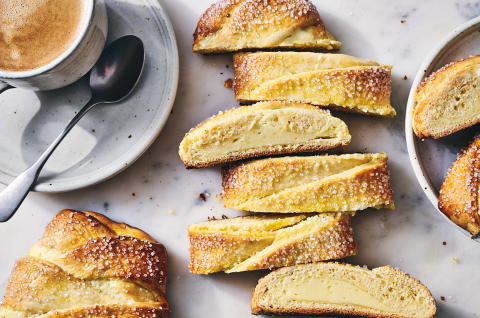Cheese Filled Sweet Braid sliced on a counter with a cup of coffee in the corner.