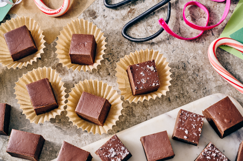 Easy Microwave Fudge cut into neat squares and placed in small paper cups with scissors and ribbon in the shot.