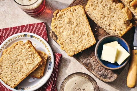 Sliced classic beer bread on a table with butter and a cutting board.