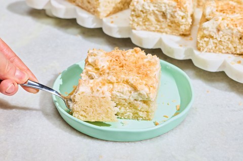 A slice of Creamy Coconut Sheet Cake on a plate with a bite on a fork