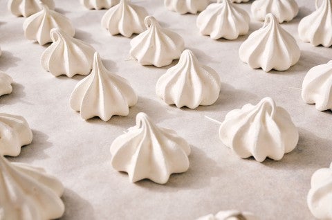 Meringue Kisses in neat rows on a counter.