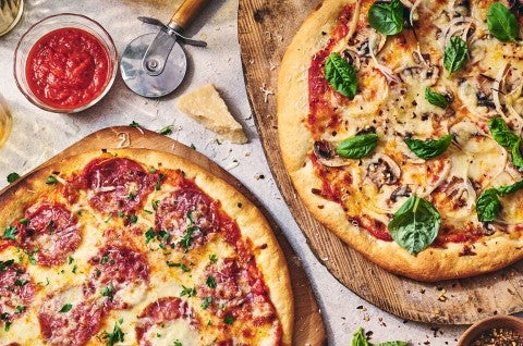 Two pizzas seen from above on wooden pizza peels