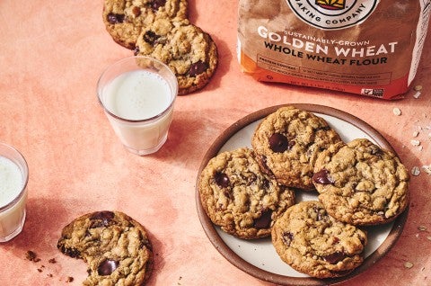 Whole Wheat Oatmeal Cookies on a plate with a glass of milk and a cookie with a bite taken out on a counter seen from above