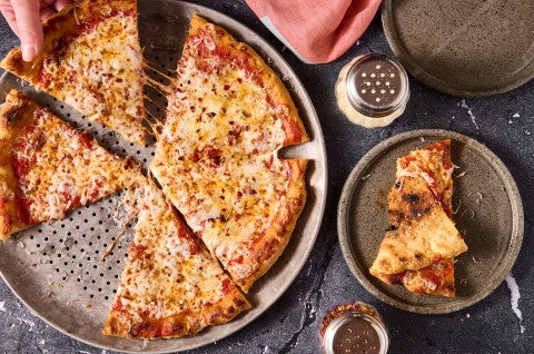 A Gluten Free NY Style Pizza on a pizza pan seen from above.