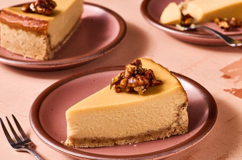 A slice of Maple Pecan Cheesecake on a pink plate, seen from the side
