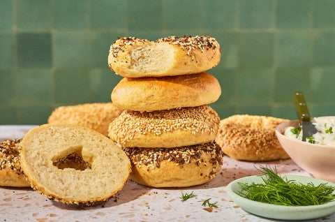 Various bagels stacked on a counter.