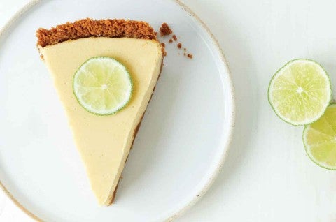 A slice of Classic Key Lime Pie with a graham cracker crust and sliced lime on top