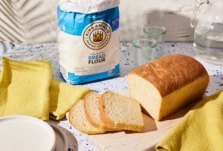 Sliced sourdough sandwich bread next to bag of bread flour