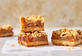 Apple Pie Bars stacked up on parchment paper