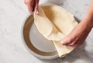 Placing pie crust dough in a pie pan 
