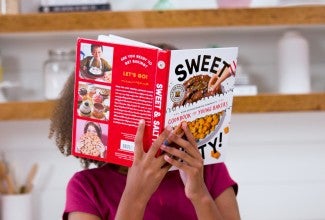 Kid holding up Sweet & Salty! kids' cookbook