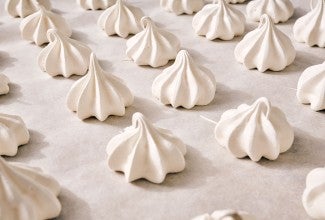 Meringue Kisses in neat rows on a counter.