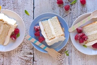 Three slices of Tender White Cake on plates, revealing their double layers of white cake and vanilla frosting.