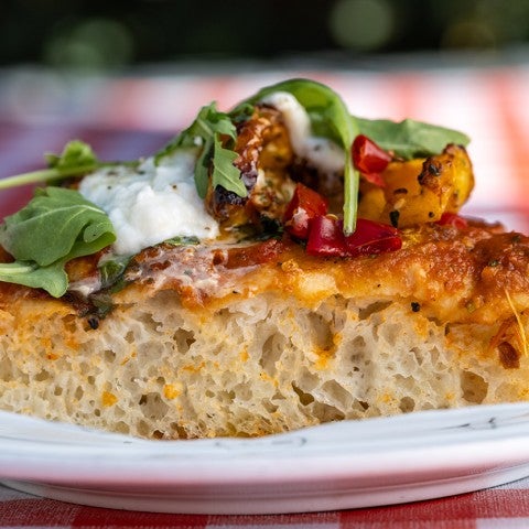 A side photograph of a slice of thick-crust pizza. - select to zoom
