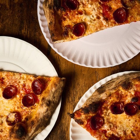 Slices of pepperoni pizza on paper plates seen from above. - select to zoom
