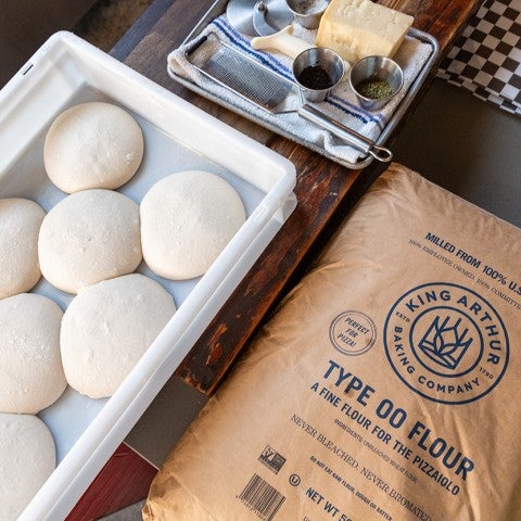 A handful of raw dough on a tray with a bag of Type 00 King Arthur Flour next to it. - select to zoom
