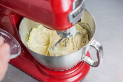 Stand mixer bowl showing smooth mixture with some liquid added
