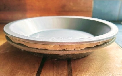 A pie pan lined with pastry dough, an identical pie pan nested on top of the dough to make a "sandwich" of pan, dough, and pan.