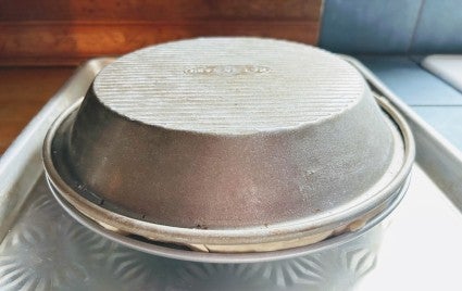 Nested pie pans with crust resting atop a round cake pan, to provide clearance from the baking sheet below.