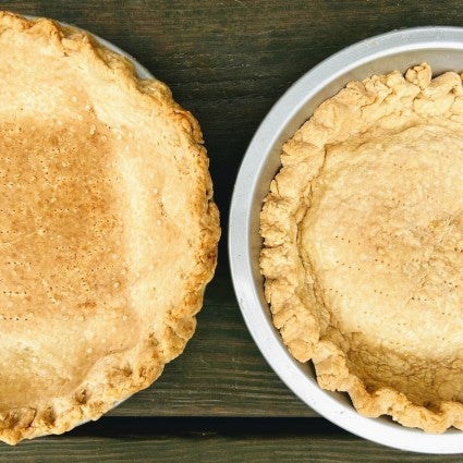 Two prebaked pie crusts side by side, one baked with a weighted liner and one without, to show the difference a liner makes.