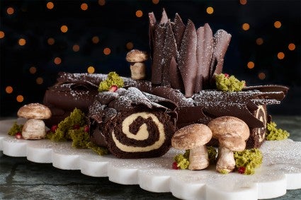 Chocolate Buche de Noel with Cookie Butter Whipped Ganache seen from the side with edible woodland decorations.