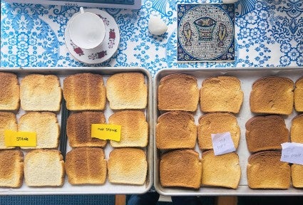 Pieces of toasted bread on half-sheet pans showing degrees of browning.