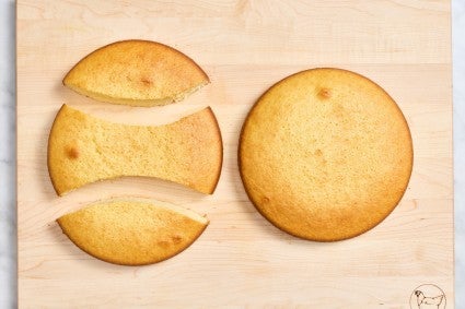 One yellow round cake next to a second round cake cut into three segments