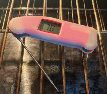 Thermapen digital thermometer laid on middle oven rack, oven turned off but oven light on. 