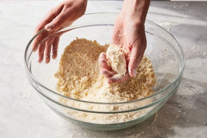 Hand holding pie crumbs in glass bowl