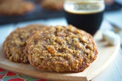 A close up side angle photo of two Oatmeal Cookies. The cookies have a crackly surface with crisp, chewy edges and soft centers.