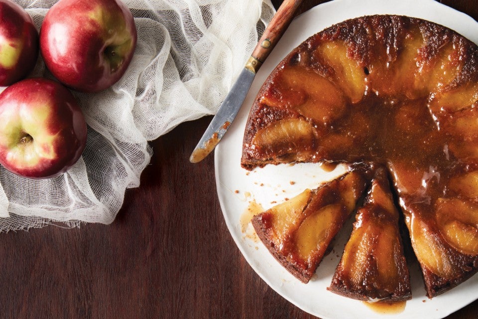 A freshly baked Apple Upside-Down Cake, inverted onto a serving platter with a slice removed.