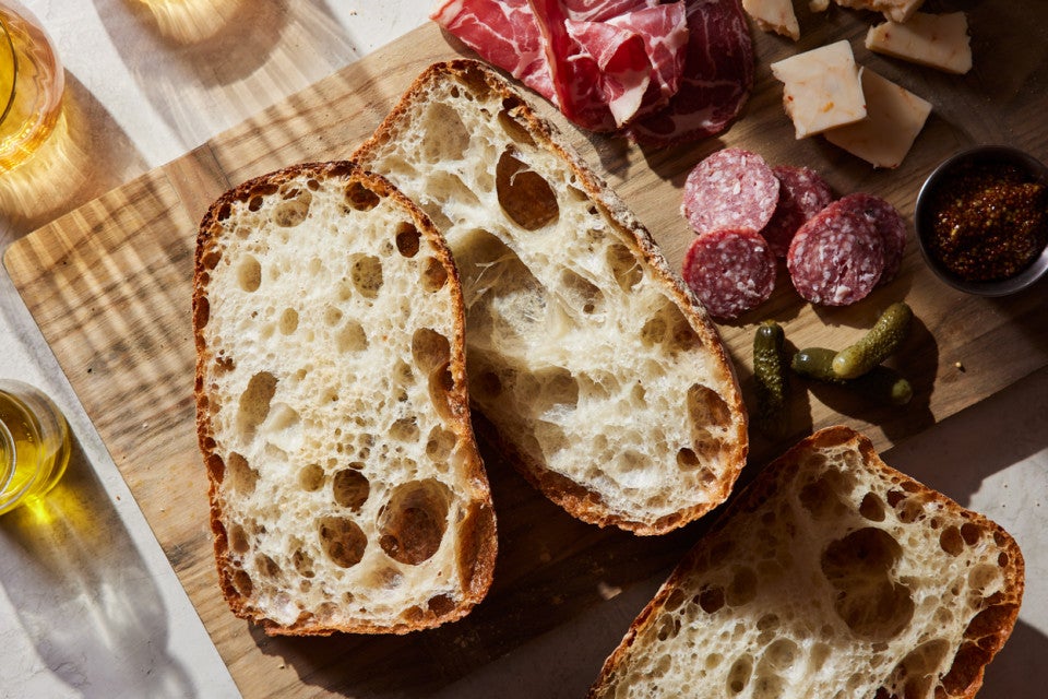 Sliced Pan de Cristal loaves on a cheese board