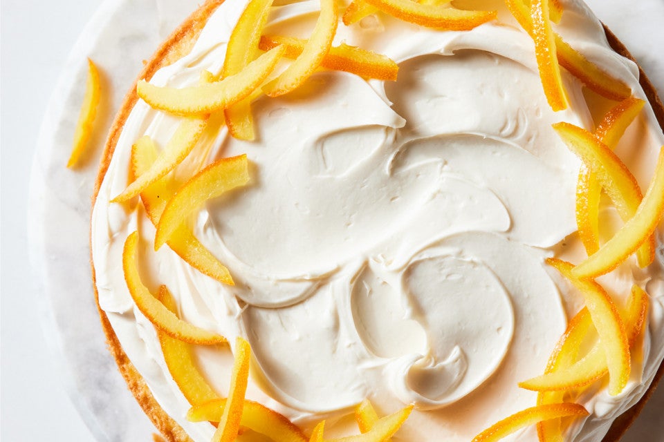 Close up of a layer cake garnished with candied oranges and a cream filling
