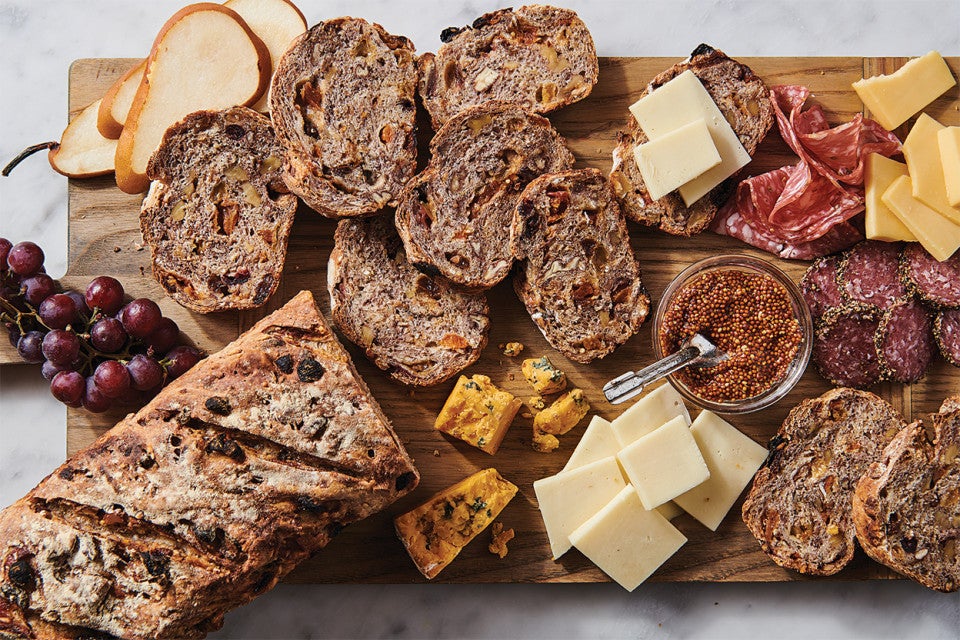 An overhead photo of a loaf artisan fruit bread that has been sliced, showing off the fruit-studded interior.