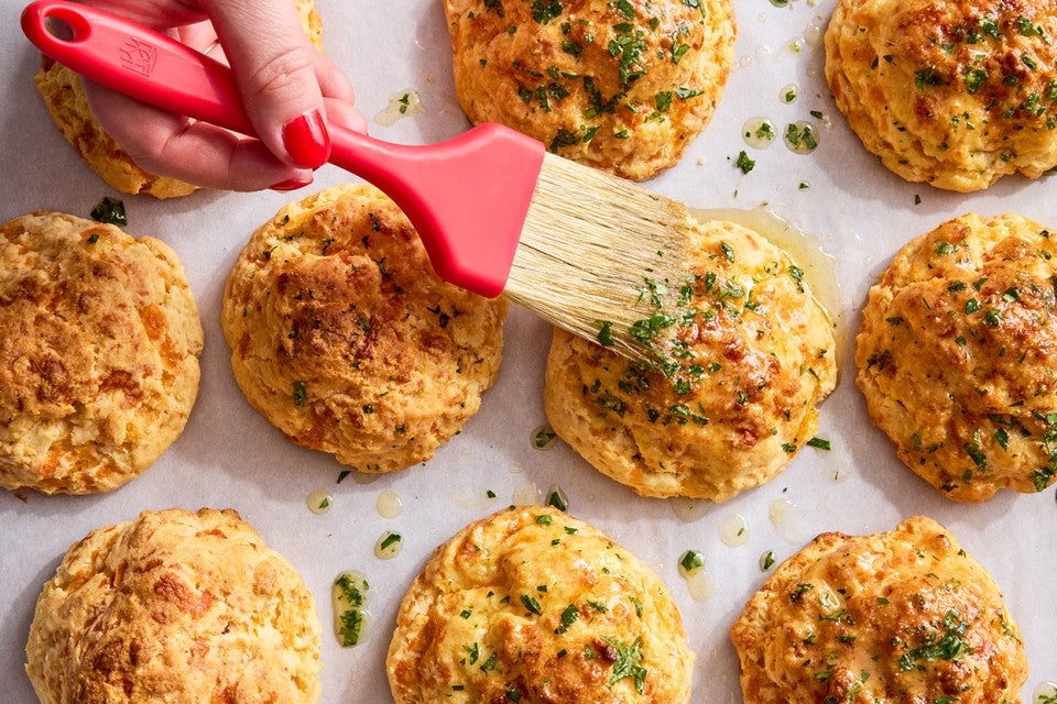Garlic Cheddar Biscuits being brushed with butter