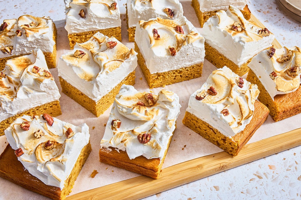 A bunch of Sweet Potato Sheet Cake with Marshmallow Frosting cut into slices on a cutting board
