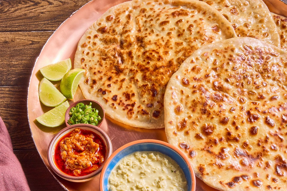 Aloo Paratha (Spiced Potato-Stuffed Flatbread) on a serving plate with lime