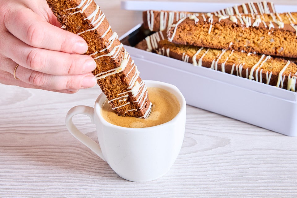 A piece of Gingerbread Biscotti being dipped into coffee
