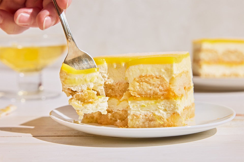 A slice of Lemon Tiramisu on a plate with a fork taking a piece out